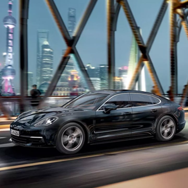 Midnight Porsche Panamera driving across bridge in city at night